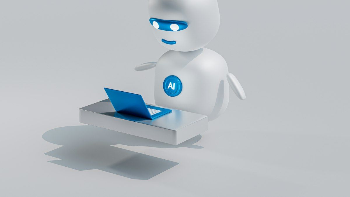 Robot putih bertuliskan AI di depan laptop