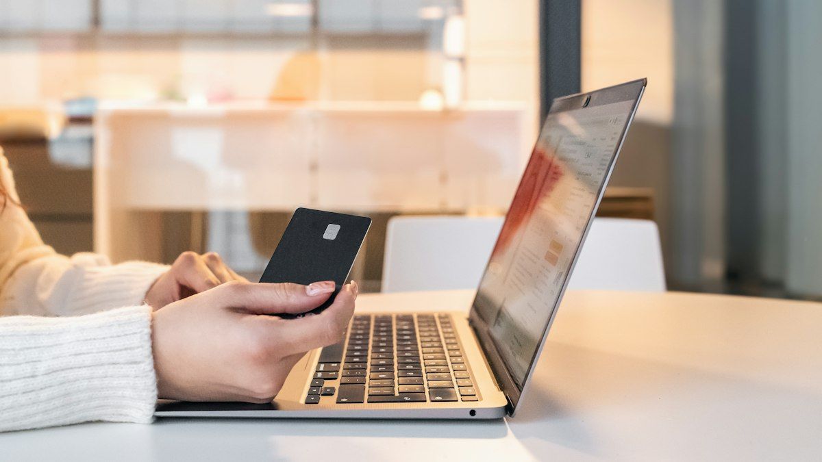A person paying with a card in front of a laptop