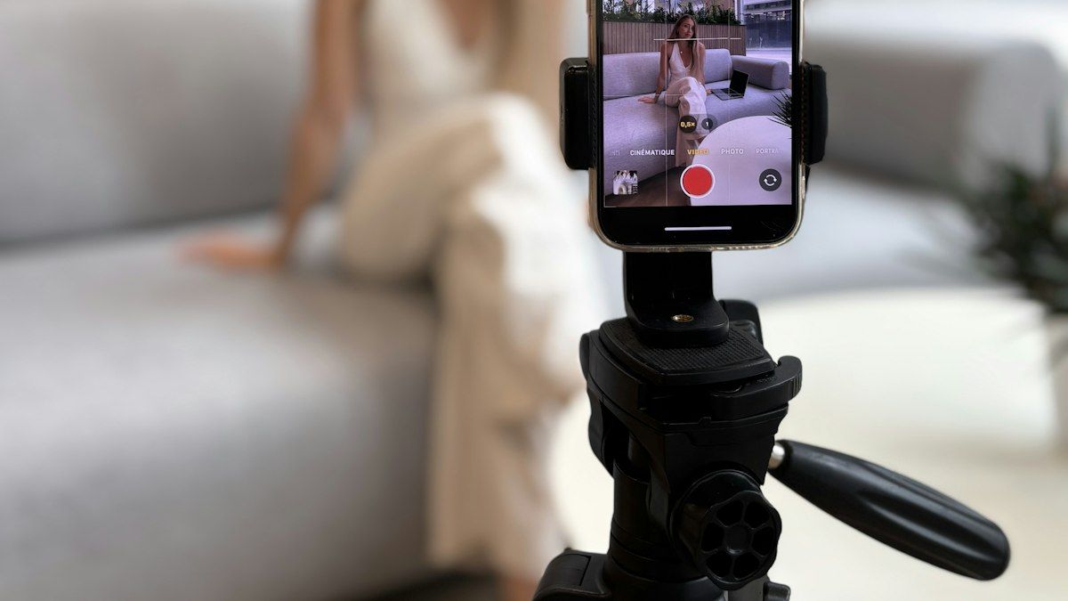 Smartphone di tripod merekam video konten di ruang tamu