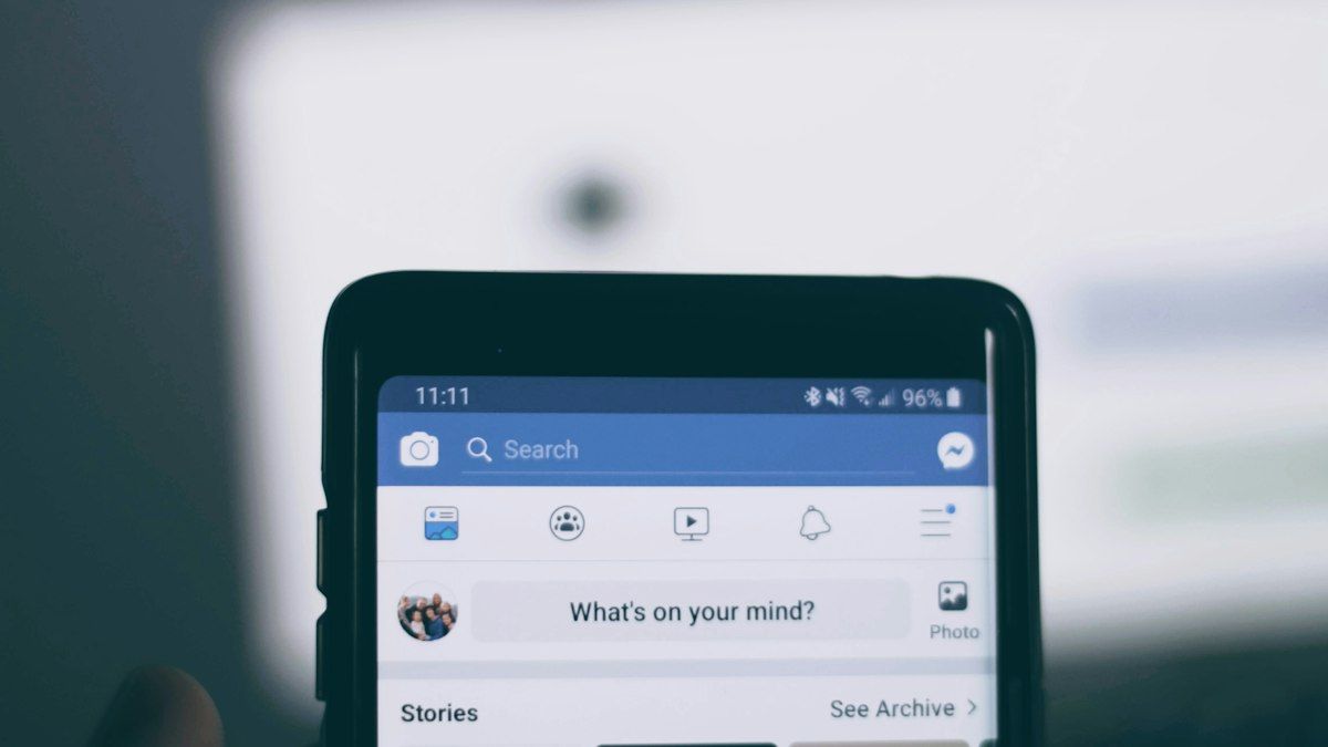 Smartphone yang menampilkan aplikasi Facebook di atas meja