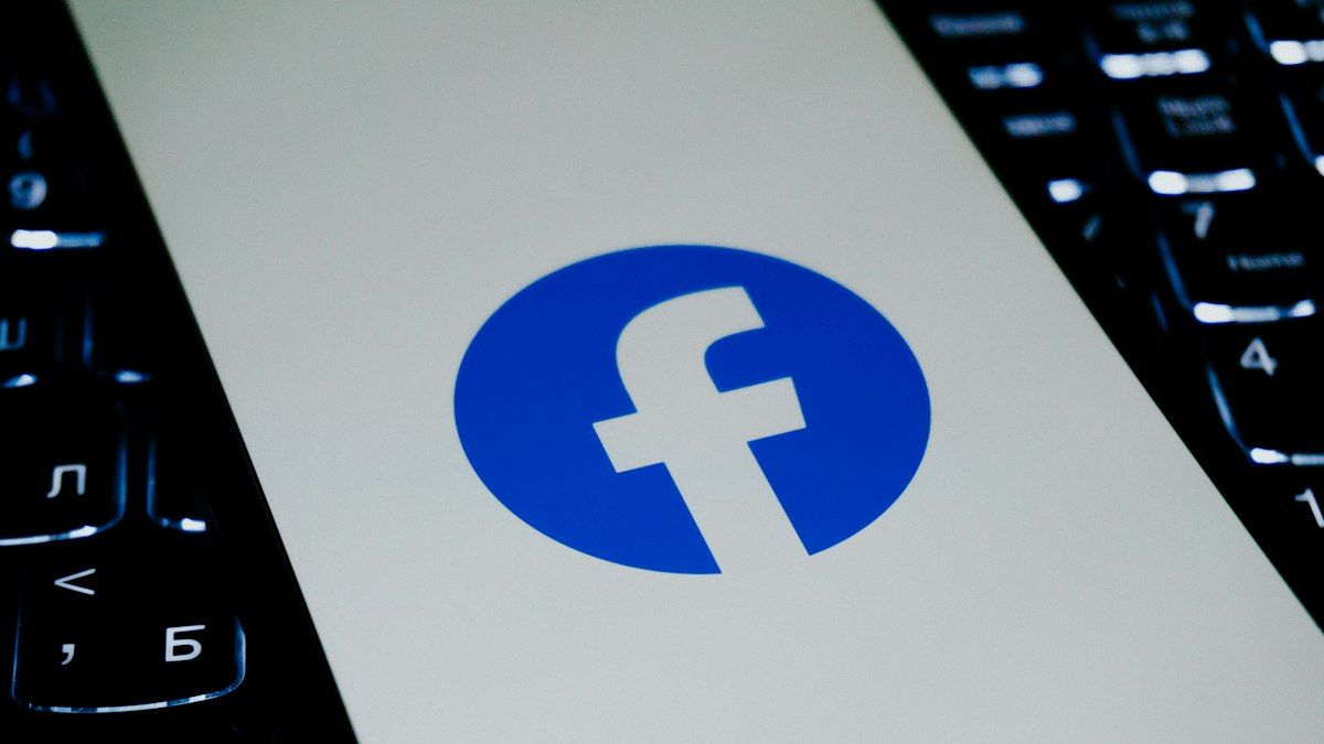 Logo Facebook di layar laptop dengan keyboard di sampingnya