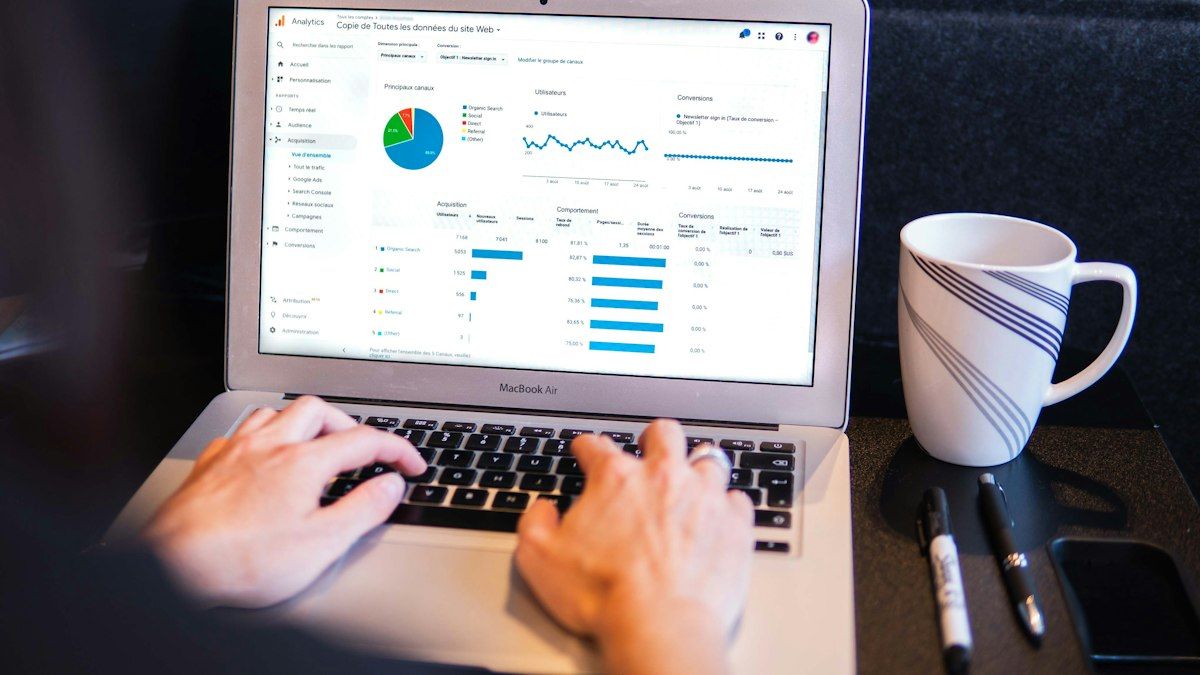 Seseorang mengetik di laptop yang menampilkan dashboard analitik