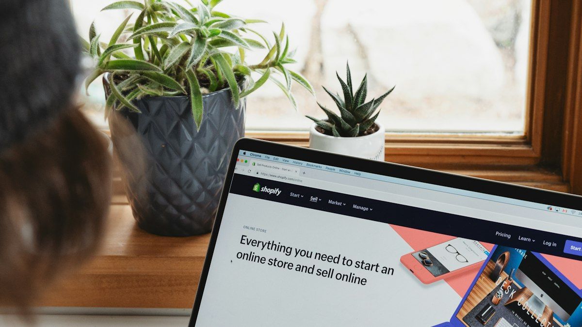Laptop menampilkan halaman toko online di meja dekat jendela