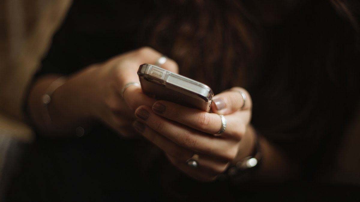 Tangan memegang smartphone di ruangan redup