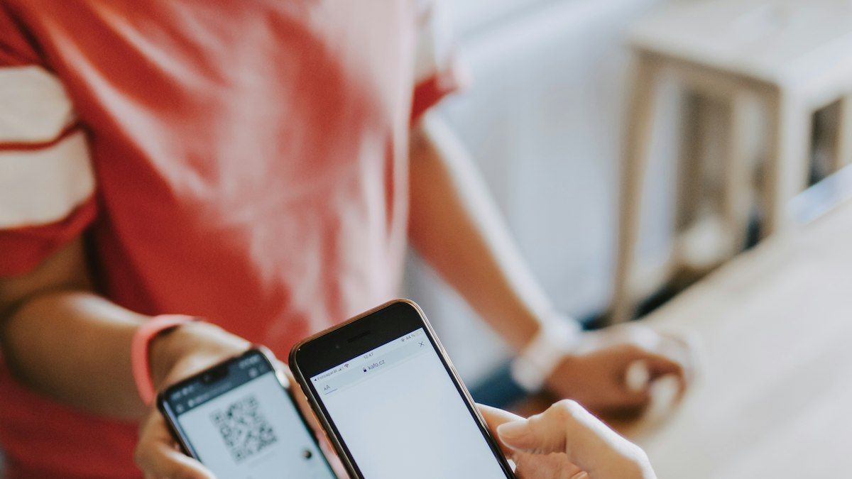Dua tangan memegang smartphone yang saling memindai kode