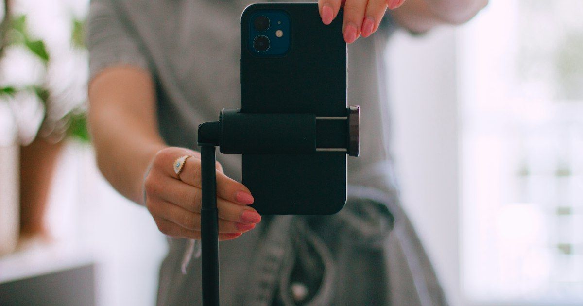 Smartphone di tripod merekam konten di dalam ruangan