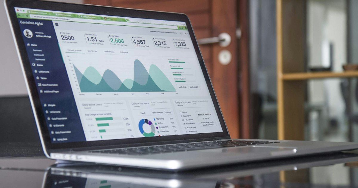 Laptop menampilkan dashboard analitik dengan grafik area