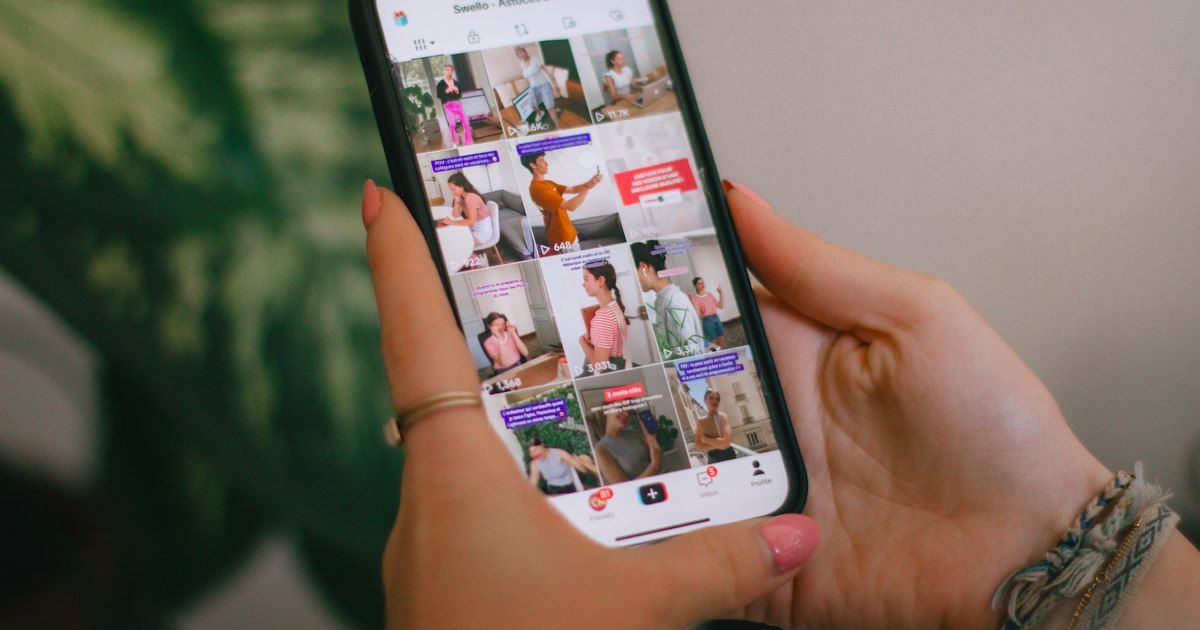 Tangan memegang smartphone yang menampilkan aplikasi video pendek