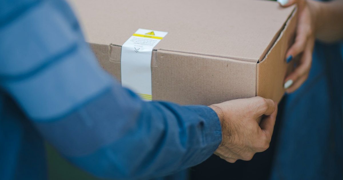 Tangan menyerahkan kotak paket kardus