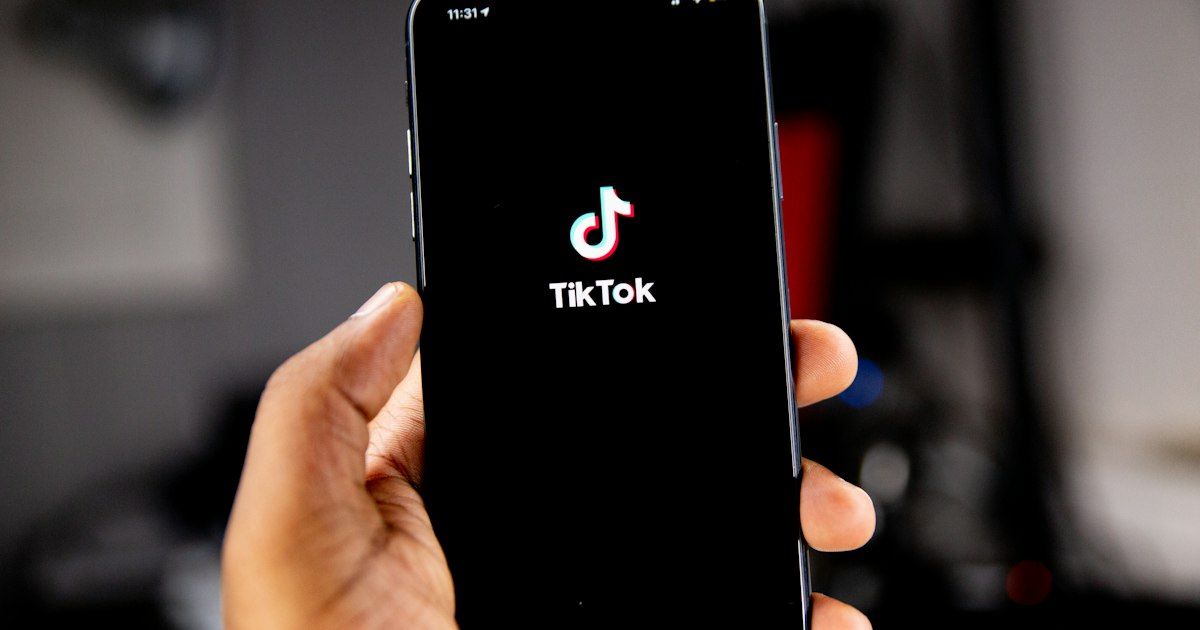 Tangan memegang smartphone yang menampilkan logo TikTok