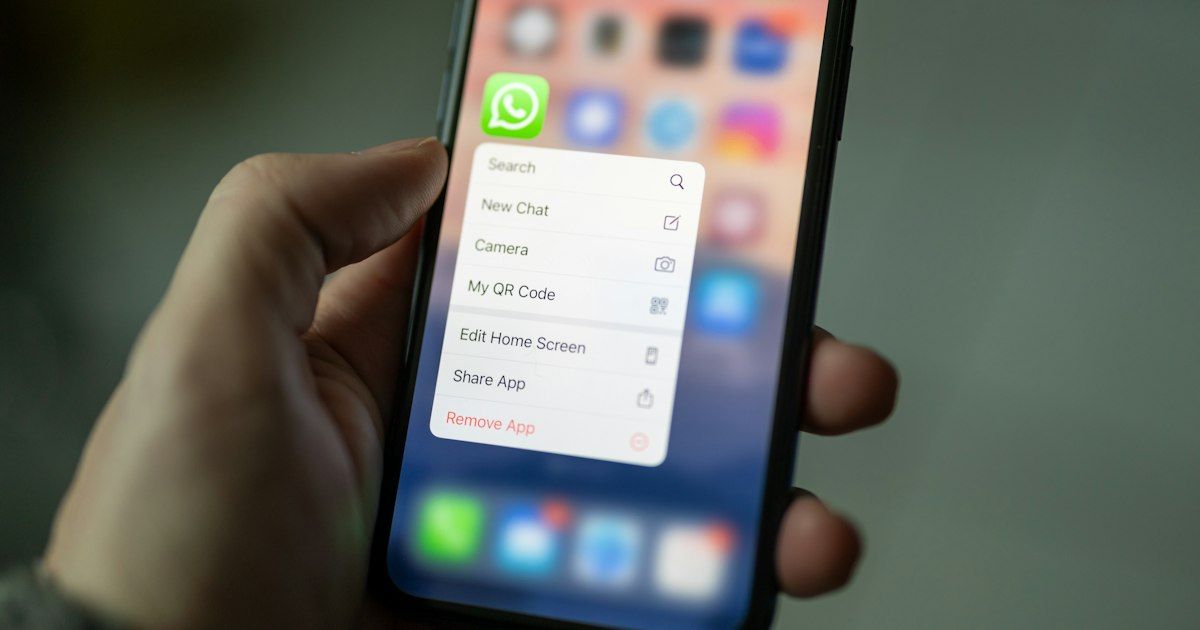Tangan memegang smartphone dengan menu aplikasi WhatsApp terbuka