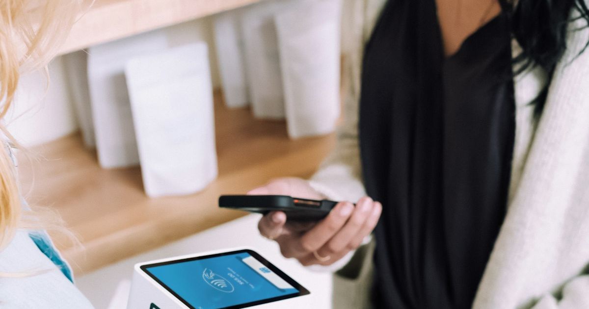 Pelanggan membayar dengan smartphone di mesin pembayaran toko
