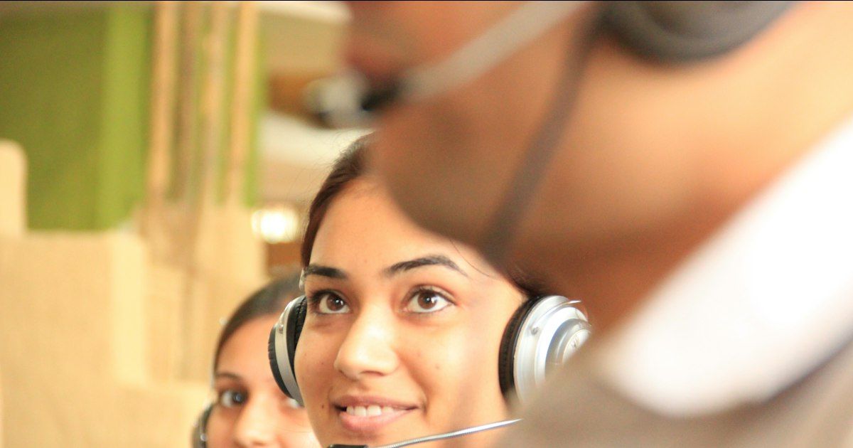 Dua agen customer service memakai headset di kantor