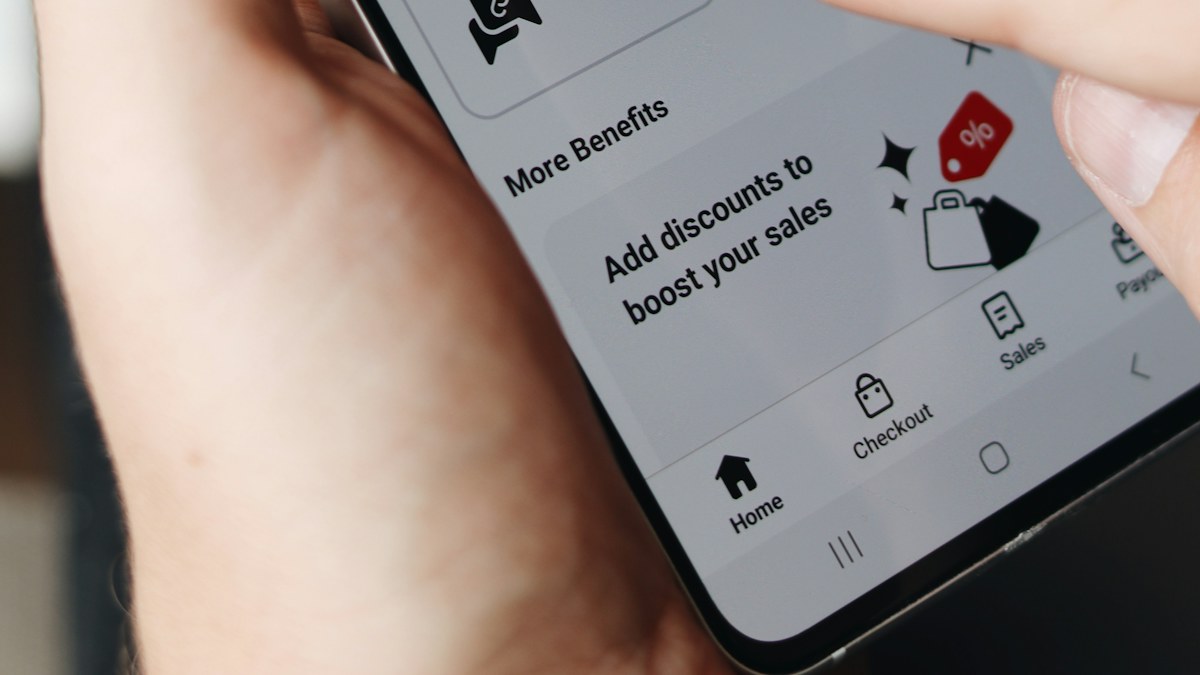 Tangan memegang smartphone yang menampilkan pesan promo diskon
