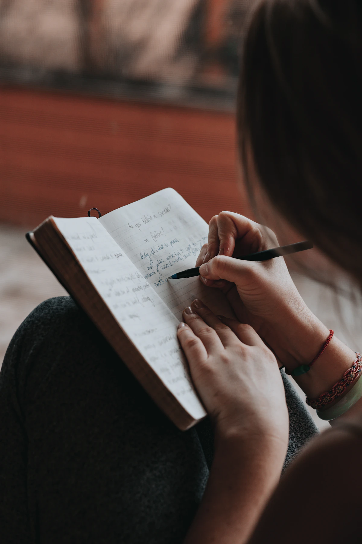 Perempuan menulis kerangka tulisan di buku catatan